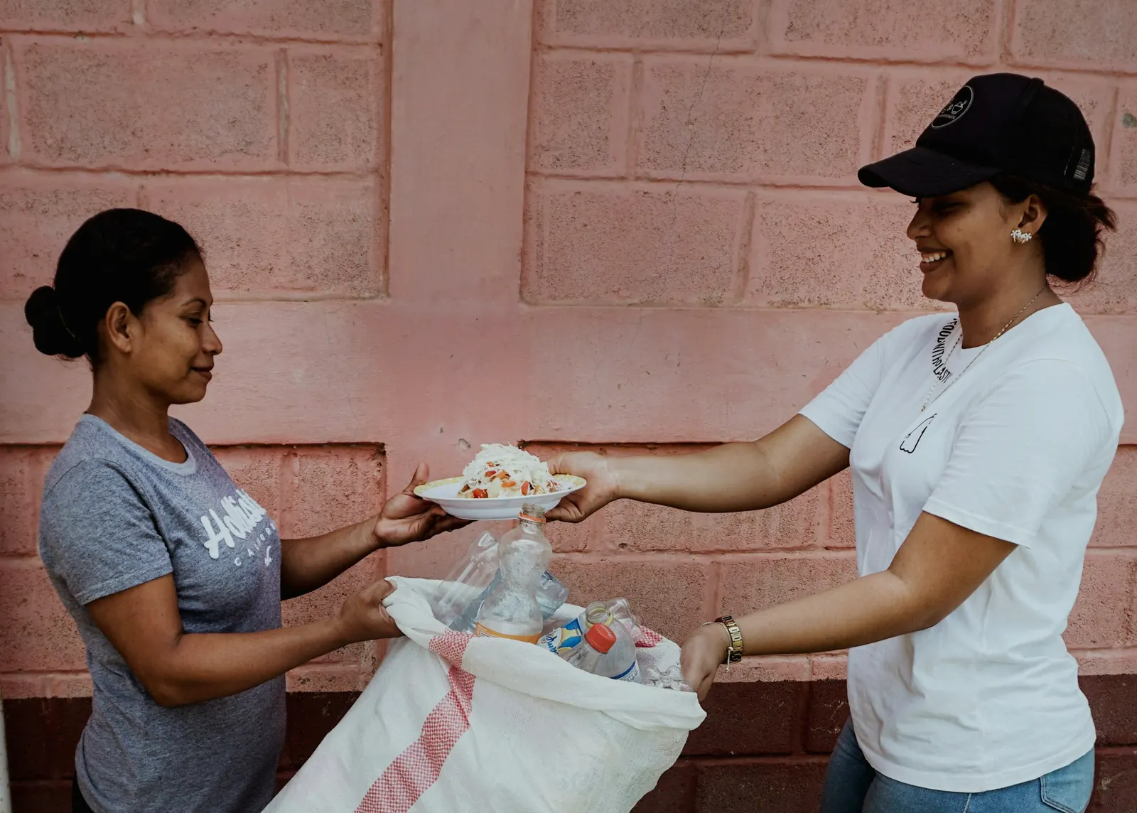 Mujer entregando un plato de comida a otra mujer